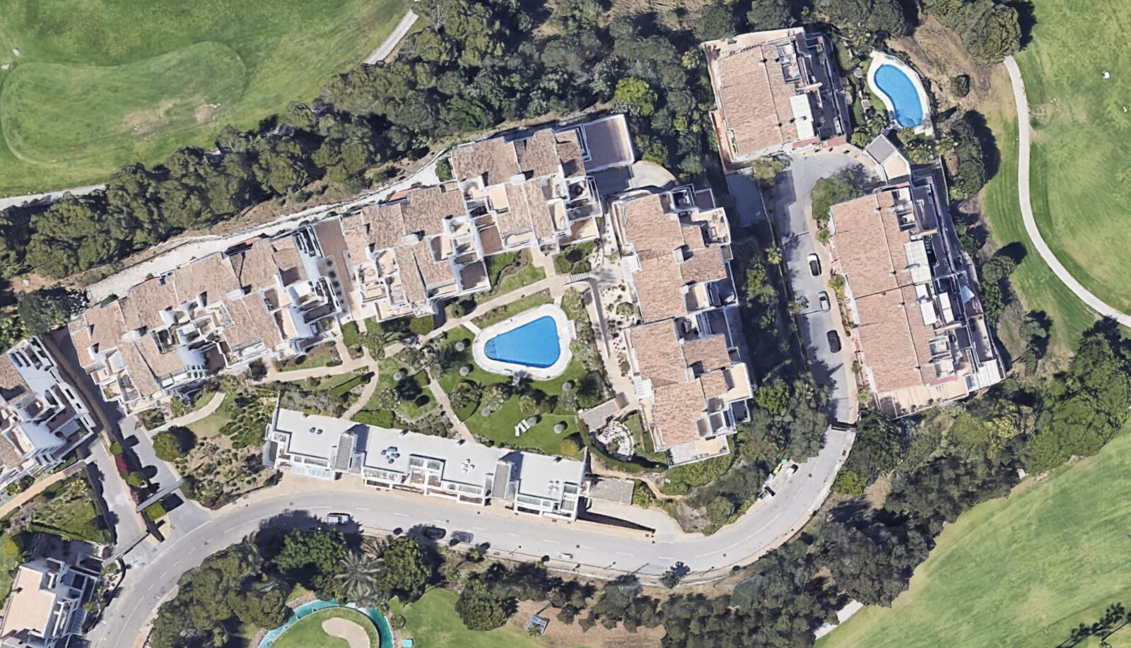 Aerial view of Golf Gardens Miraflores — the buildings around the central gardens and pool, golf course either side